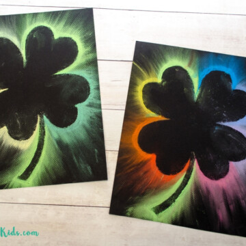 Four leaf clover art using chalk pastels on black paper. Kids art project for St. Patrick's Day.