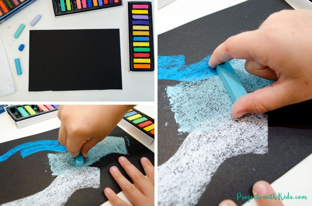 Using a flat edge of chalk pastels to draw thick blue lines on black paper.
