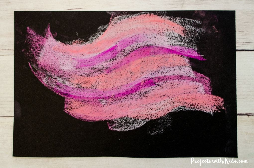Different shades of pink chalk pastels layered together on black pastel paper. 