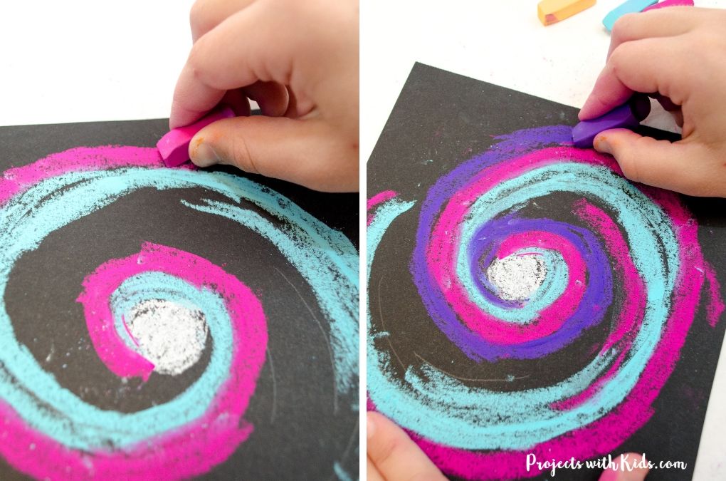 Drawing a galaxy spiral on black paper with pink and purple chalk pastels