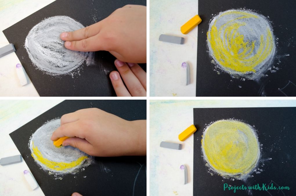 Adding in yellow chalk pastel to a full moon on black paper as part of a Halloween pumpkin art project.