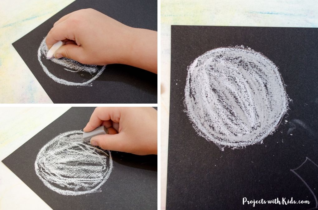 Using chalk pastels to create a full moon on black paper.