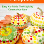 Mini white pumpkins with dots on them painted with q-tips on fall leaves for a kid-made Thanksgiving centerpiece craft.