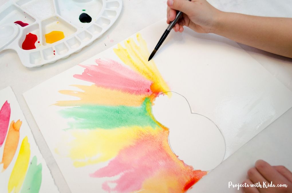 Painting feathers for a Thanksgiving turkey craft with watercolors on paper