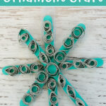Snowflake ornament craft made with popsicle sticks and paper quilling.
