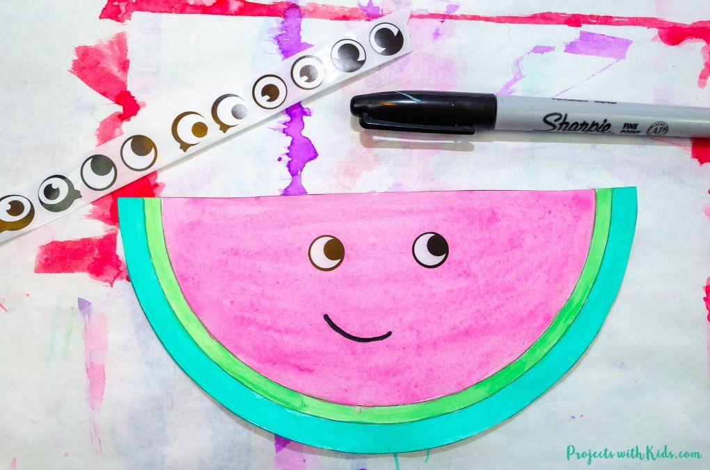 Adding eyes and a mouth to a watermelon kids craft
