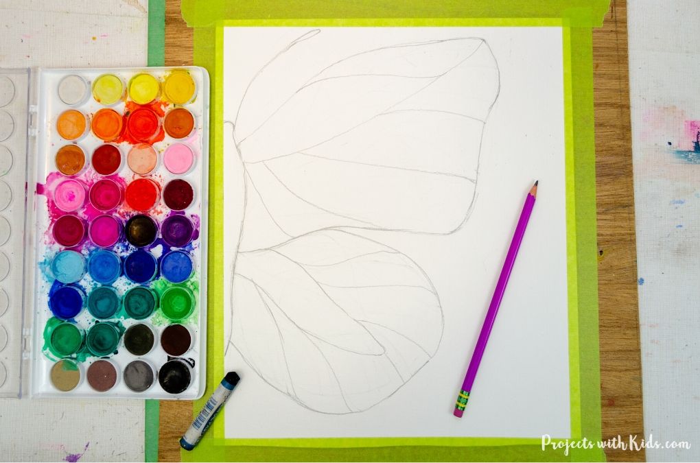 Drawing a butterfly on watercolor paper with a pencil.