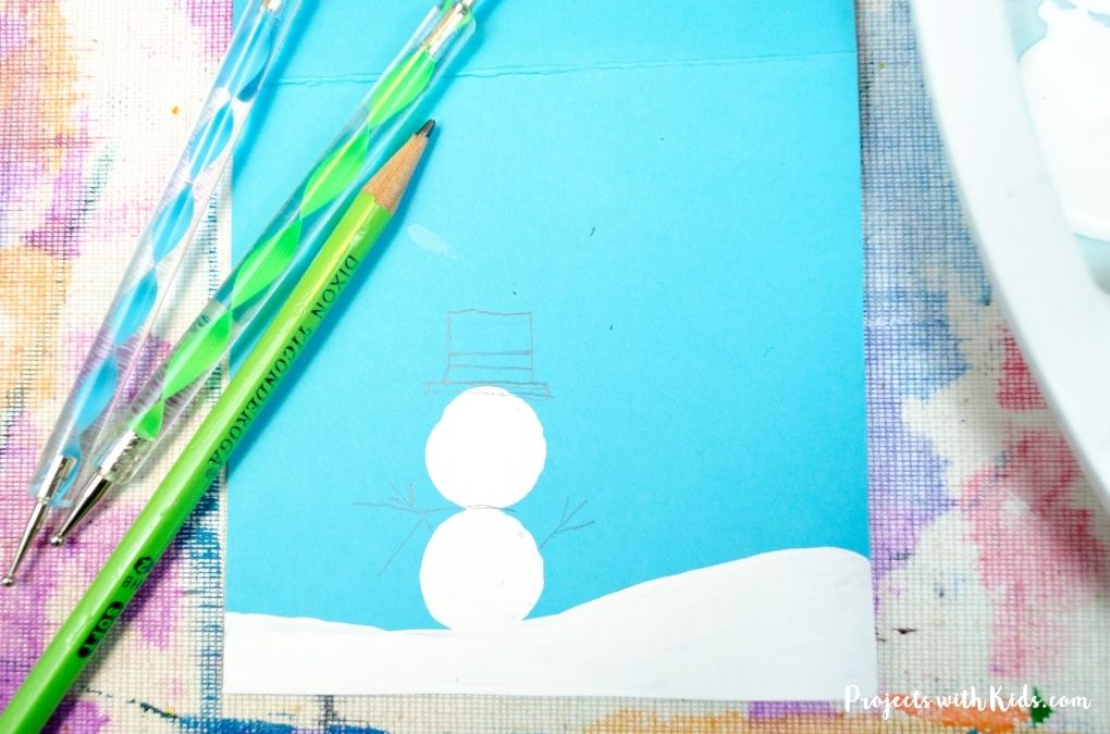 Drawing a hat and scarf on a cork printed snowman painting idea for kids.