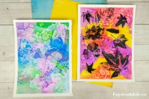 Leaf printing art with colorful watercolor background and black and white printed leaves.