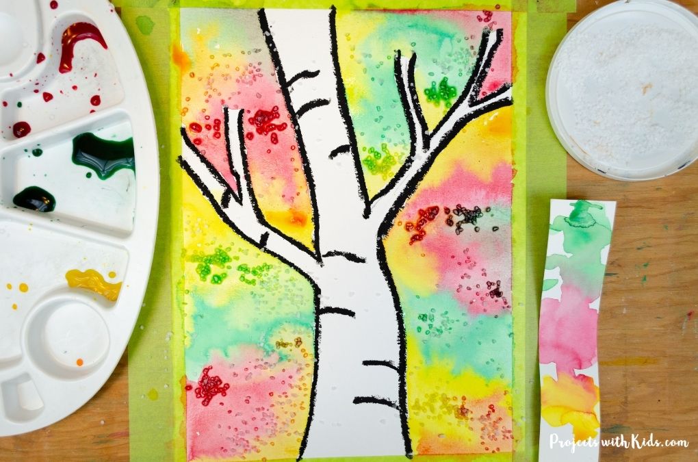 Sprinkling salt on a watercolor birch tree painting for kids