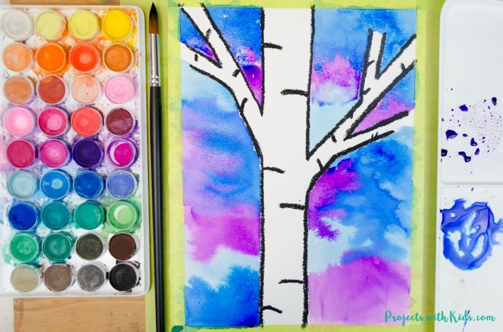Painting with blue and purple watercolors for a winter tree painting idea for kids.