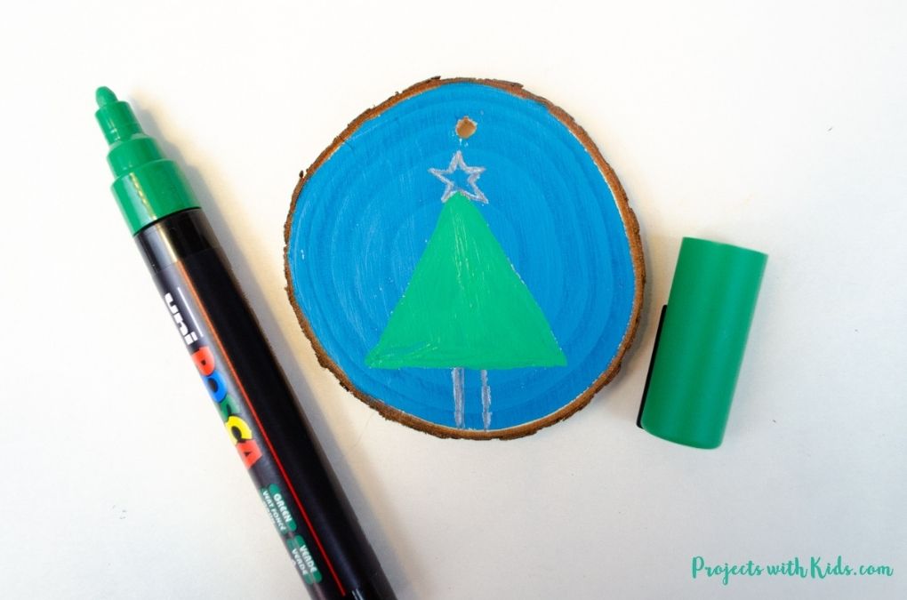 Coloring in a simple tree on a wood slice ornament with a paint pen