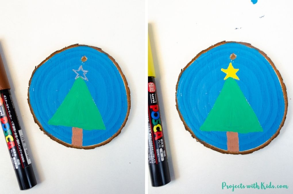 Coloring a simple tree and star with paint pens on a wood slice