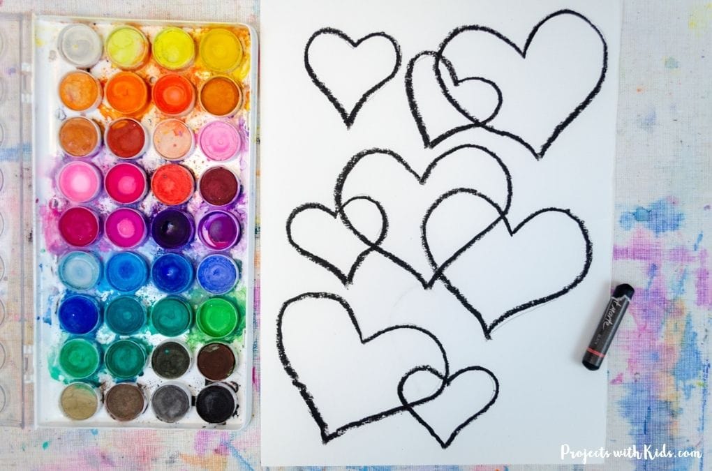 Drawing hearts with black oil pastel on watercolor paper