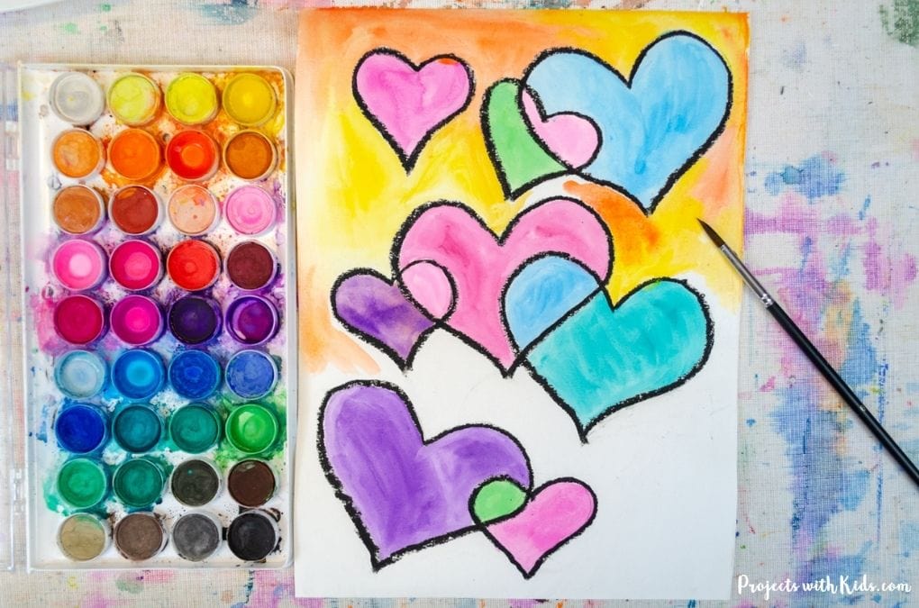 painting a yellow and orange background on a watercolor hearts art project for kids