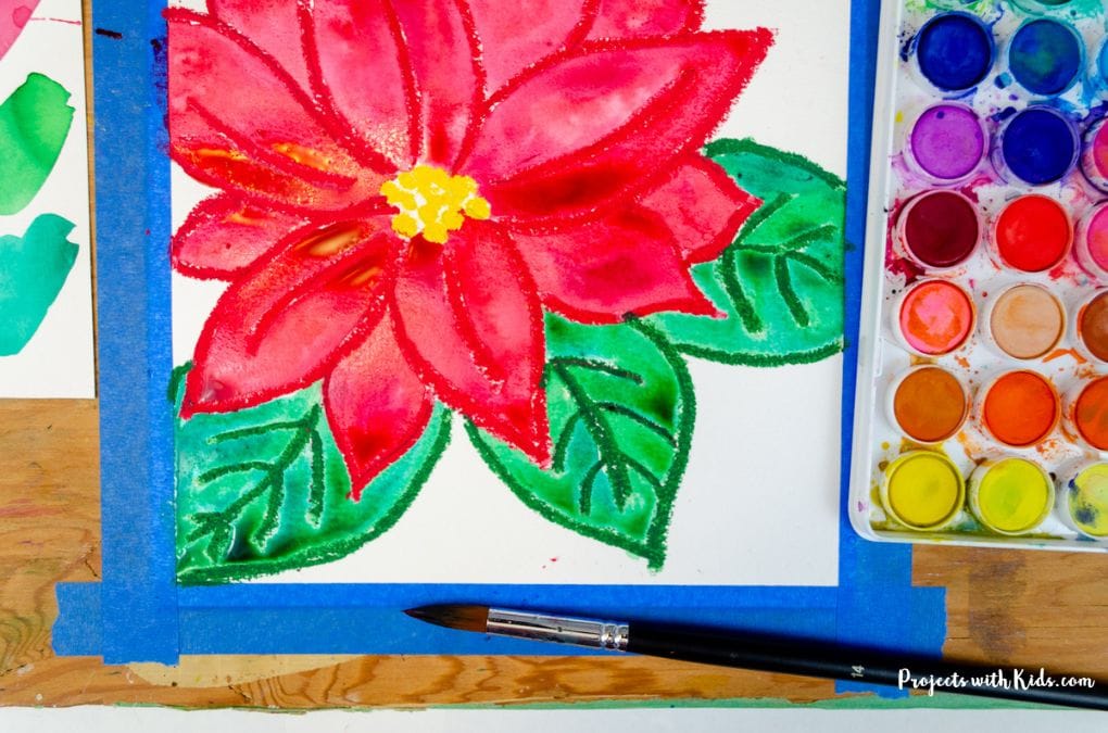 Painting leaves with green watercolor paint on a poinsettia art project winter painting idea for kids