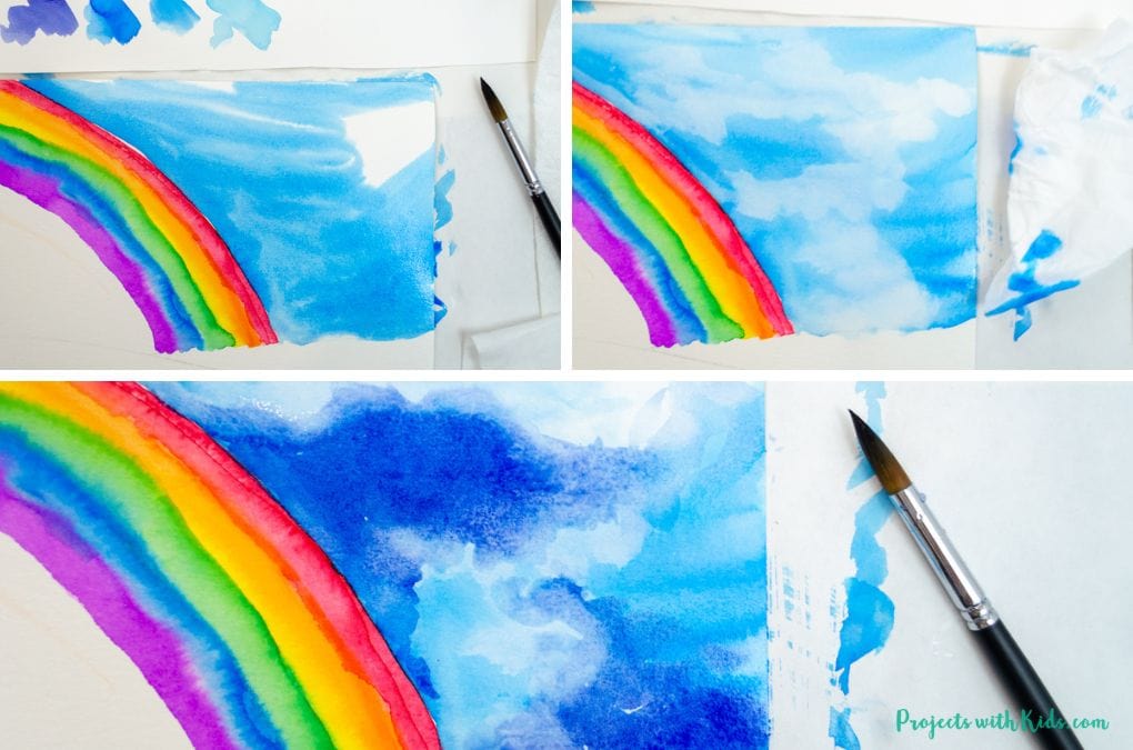 Using a tissue and watercolor paint to paint in a stormy sky and create clouds.