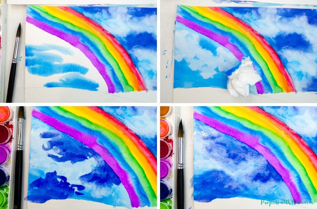 Painting clouds in a sky with a rainbow.