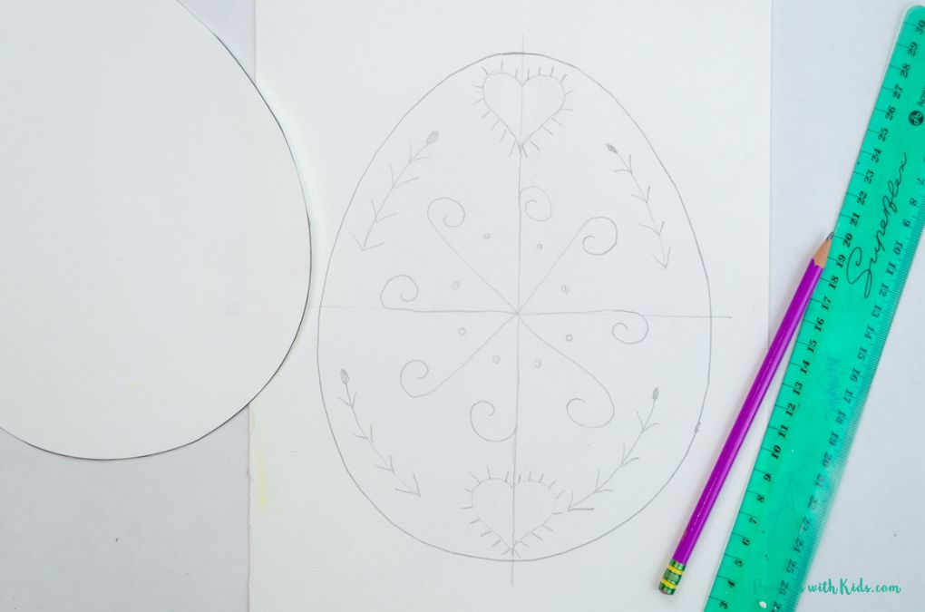 Drawing traditional Ukrainian designs on an Easter egg template for a watercolor painting art project for kids.