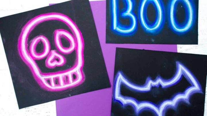 Halloween art project that looks like a neon sign with a purple bat, a blue sign that says Boo, and a pink skeleton. Art project idea for kids.